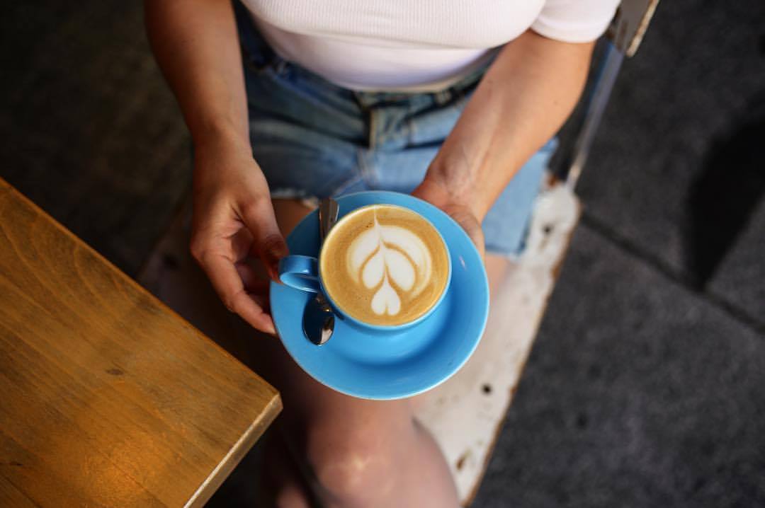 Woman holding a latte at Cafe Neudstadt