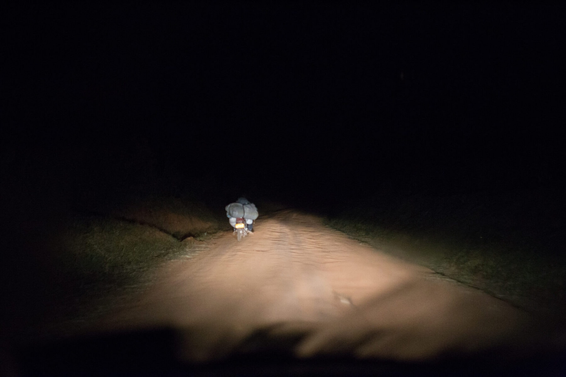 Ugandská silnice za tmy, pouze prach, neosvětlená vozidla a díry